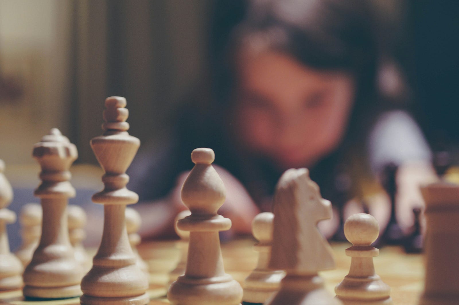 A chess game in the foreground with a blurred person in the background